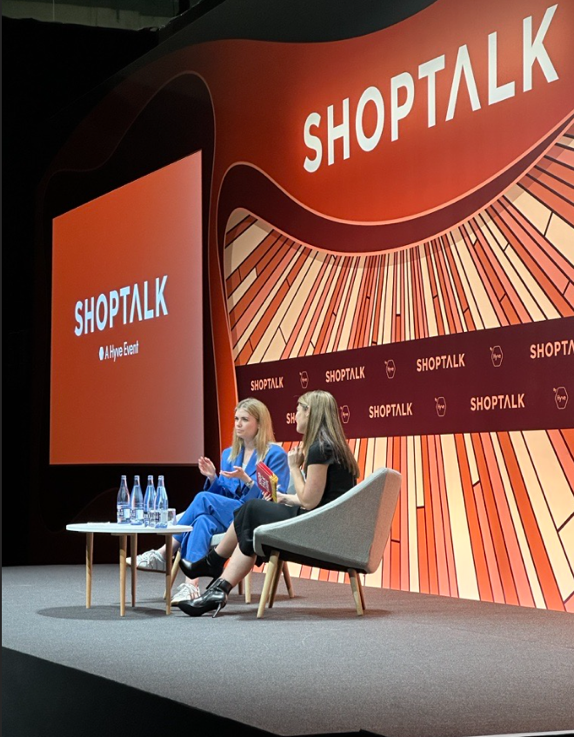 A group of women sitting in chairs on a stage Description automatically generated with medium confidence